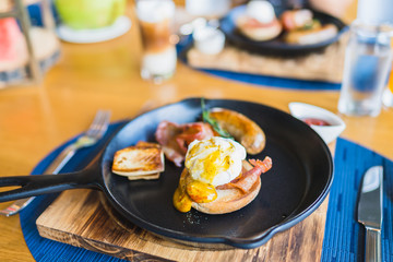 Breakfast set with egg benedict sausage in hot pan