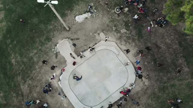 BARILOCHE, ARGENTINA - CIRCA MAY 2019: Young people jumping in the halfpipe in the Skate-park, aerial view, 4k.