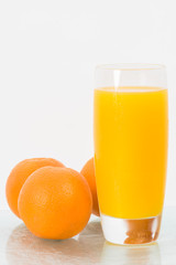 Concept image for healthy living showing a glass of  freshly squeezed orange juice and the fruit isolated against a white background.