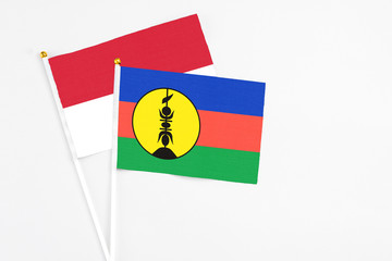 New Caledonia and Indonesia stick flags on white background. High quality fabric, miniature national flag. Peaceful global concept.White floor for copy space.