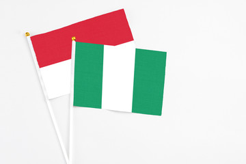 Fototapeta premium Nigeria and Indonesia stick flags on white background. High quality fabric, miniature national flag. Peaceful global concept.White floor for copy space.