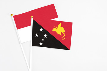Papua New Guinea and Indonesia stick flags on white background. High quality fabric, miniature national flag. Peaceful global concept.White floor for copy space.
