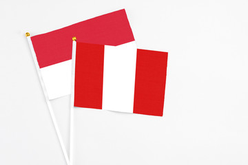 Peru and Indonesia stick flags on white background. High quality fabric, miniature national flag. Peaceful global concept.White floor for copy space.