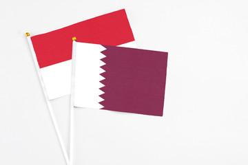 Qatar and Indonesia stick flags on white background. High quality fabric, miniature national flag. Peaceful global concept.White floor for copy space.