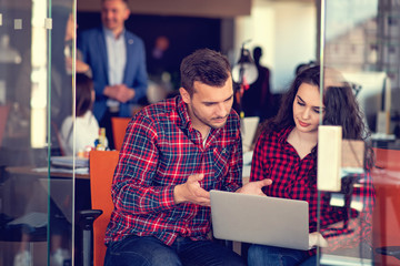 Two colleagues discussing work on a laptop.