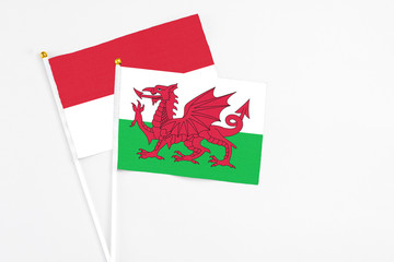 Wales and Indonesia stick flags on white background. High quality fabric, miniature national flag. Peaceful global concept.White floor for copy space.