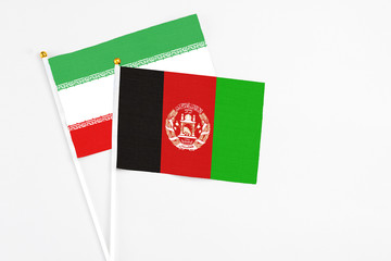 Afghanistan and Iran stick flags on white background. High quality fabric, miniature national flag. Peaceful global concept.White floor for copy space.