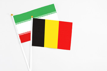 Belgium and Iran stick flags on white background. High quality fabric, miniature national flag. Peaceful global concept.White floor for copy space.