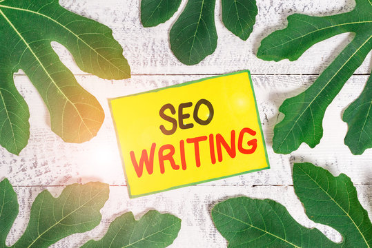 Handwriting text writing Seo Writing. Conceptual photo grabbing the attention of the search engines using specific word Leaves surrounding notepaper above a classic wooden table as the background