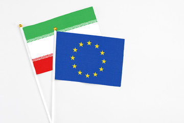 European Union and Iran stick flags on white background. High quality fabric, miniature national flag. Peaceful global concept.White floor for copy space.