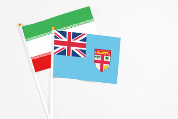 Fototapeta premium Fiji and Iran stick flags on white background. High quality fabric, miniature national flag. Peaceful global concept.White floor for copy space.
