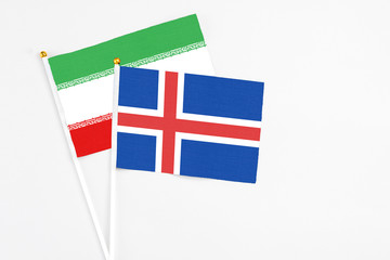 Iceland and Iran stick flags on white background. High quality fabric, miniature national flag. Peaceful global concept.White floor for copy space.