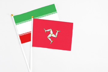Isle Of Man and Iran stick flags on white background. High quality fabric, miniature national flag. Peaceful global concept.White floor for copy space.
