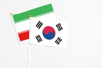 South Korea and Iran stick flags on white background. High quality fabric, miniature national flag. Peaceful global concept.White floor for copy space.