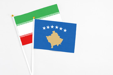 Kosovo and Iran stick flags on white background. High quality fabric, miniature national flag. Peaceful global concept.White floor for copy space.