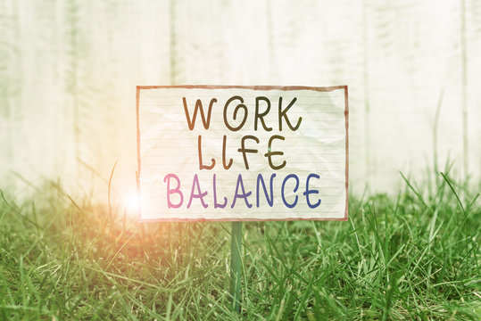 Text sign showing Work Life Balance. Business photo text Division of time between working or family and leisure Crumpled paper attached to a stick and placed in the green grassy land