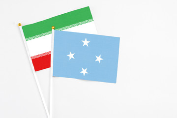 Micronesia and Iran stick flags on white background. High quality fabric, miniature national flag. Peaceful global concept.White floor for copy space.