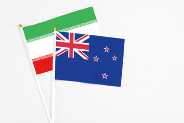 Fototapeta premium New Zealand and Iran stick flags on white background. High quality fabric, miniature national flag. Peaceful global concept.White floor for copy space.