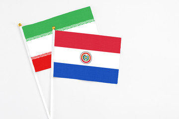 Paraguay and Iran stick flags on white background. High quality fabric, miniature national flag. Peaceful global concept.White floor for copy space.