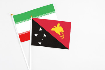 Papua New Guinea and Iran stick flags on white background. High quality fabric, miniature national flag. Peaceful global concept.White floor for copy space.