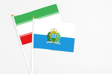 San Marino and Iran stick flags on white background. High quality fabric, miniature national flag. Peaceful global concept.White floor for copy space.