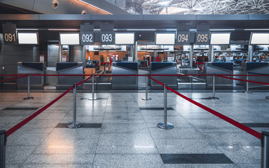 Front view of a check-in area in a modern airport: luggage accept terminals with baggage handling belt conveyor system, empty white information LCD screens mockups, indexed check-in desks, red ribbons