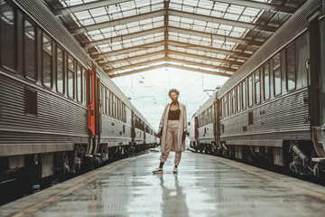 African woman in a white cloak and spectacles is standing in the center of a station between two...