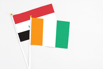 Cote D'Ivoire and Iraq stick flags on white background. High quality fabric, miniature national flag. Peaceful global concept.White floor for copy space.