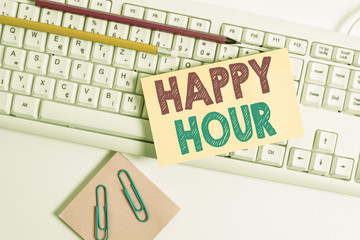 Conceptual hand writing showing Happy Hour. Concept meaning when drinks are sold at reduced prices in a bar or restaurant White keyboard with note paper and clips on white background