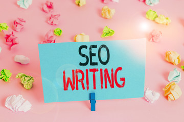 Handwriting text Seo Writing. Conceptual photo grabbing the attention of the search engines using specific word Colored crumpled papers empty reminder pink floor background clothespin