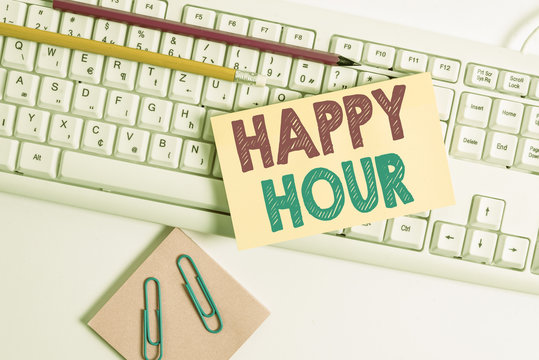 Conceptual hand writing showing Happy Hour. Concept meaning when drinks are sold at reduced prices in a bar or restaurant White keyboard with note paper and clips on white background
