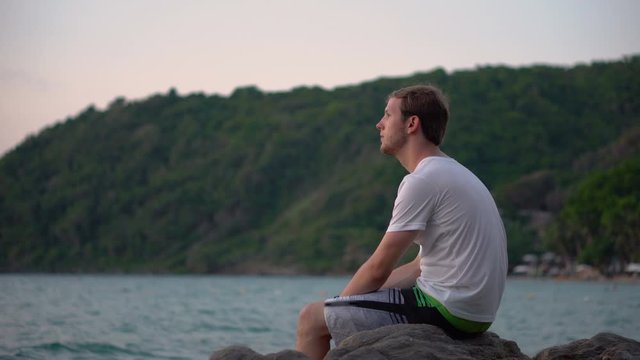 Sorrowful Sad Young Man Sitting By Tropical Beach Looking At Ocean