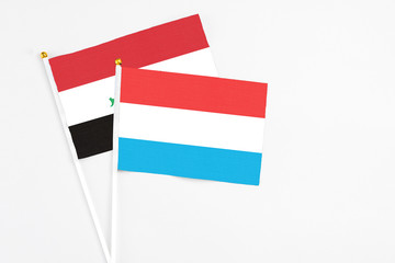 Luxembourg and Iraq stick flags on white background. High quality fabric, miniature national flag. Peaceful global concept.White floor for copy space.