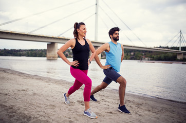 Fitness couple on a river beach doing stretching