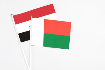Madagascar and Iraq stick flags on white background. High quality fabric, miniature national flag. Peaceful global concept.White floor for copy space.