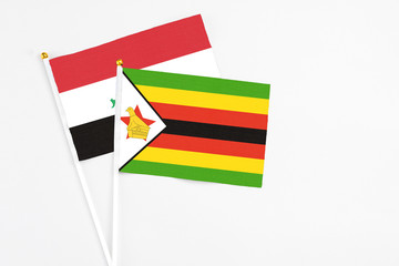 Zimbabwe and Iraq stick flags on white background. High quality fabric, miniature national flag. Peaceful global concept.White floor for copy space.