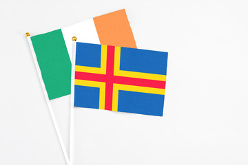 Aland Islands and Ireland stick flags on white background. High quality fabric, miniature national flag. Peaceful global concept.White floor for copy space