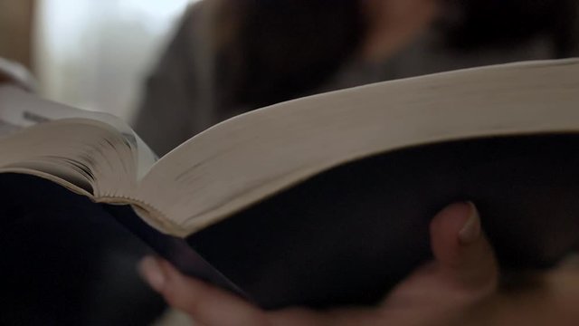 woman reads a book turns over the pages, bible, slow motion