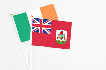 Bermuda and Ireland stick flags on white background. High quality fabric, miniature national flag. Peaceful global concept.White floor for copy space