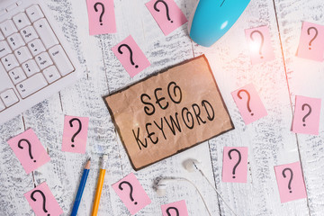 Conceptual hand writing showing Seo Keyword. Concept meaning phrases in your web content that help showing find your site Writing tools and scribbled paper on top of the wooden table