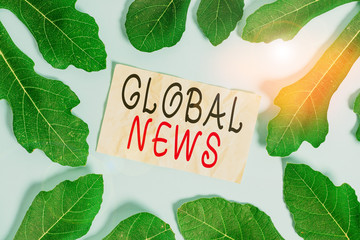 Conceptual hand writing showing Global News. Concept meaning world noteworthy information about recent or important events Leaves surrounding notepaper above empty soft pastel table