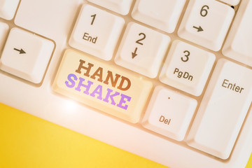 Conceptual hand writing showing Hand Shake. Concept meaning an act showing that you have made an agreement or greeting White pc keyboard with note paper above the white background