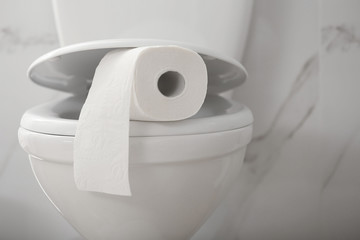 Paper roll on toilet bowl in bathroom