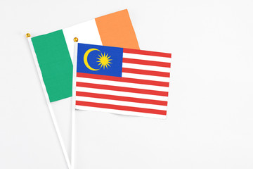 Malaysia and Ireland stick flags on white background. High quality fabric, miniature national flag. Peaceful global concept.White floor for copy space