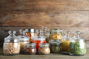 Obraz na płótnie Canvas Glass jars with different types of groats and pasta on wooden table