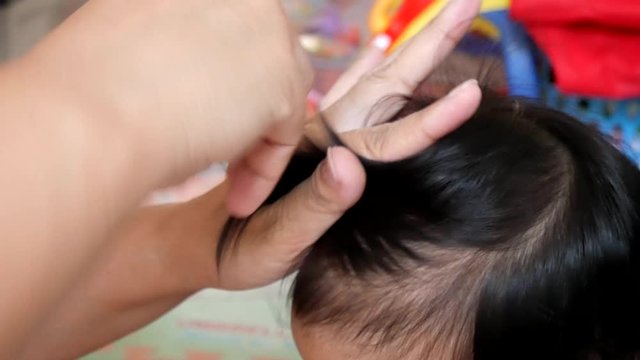 Asian mother is hair tied for her baby girl