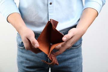Man showing empty wallet on light background, closeup