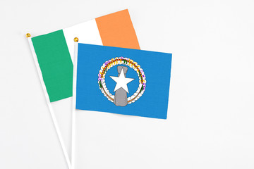 Northern Mariana Islands and Ireland stick flags on white background. High quality fabric, miniature national flag. Peaceful global concept.White floor for copy space