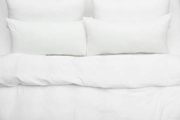Soft white pillows and blanket on bed, top view