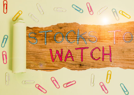 Writing note showing Stocks To Watch. Business concept for being heavy broker and watch every increase decrease Paper clip and torn cardboard on wood classic table backdrop
